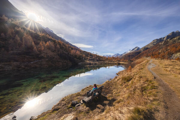 A girl admiring the Grundsee in Lotschental valley in autumn. Bernese Alps, canton of Valais, Switzerland.