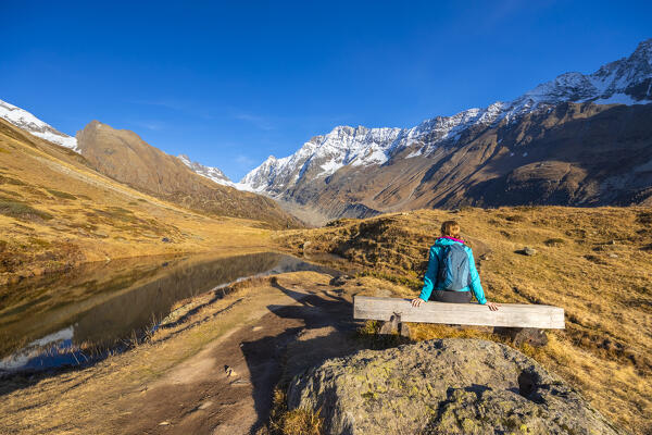 A girl admiring the Guggisee in Lotschental valley in autumn. Bernese Alps, canton of Valais, Switzerland.