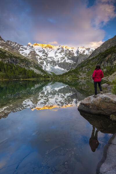 Summer view of a girl admiring sunset near the Aviolo lake in the Adamello park. Edolo,Brescia province, Italy, Europe.