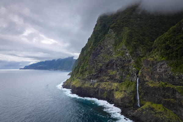 Aerial view of a waterfall going directly in the ocean on the coast of Seixal in spring. Madeira, Portugal, Europe.