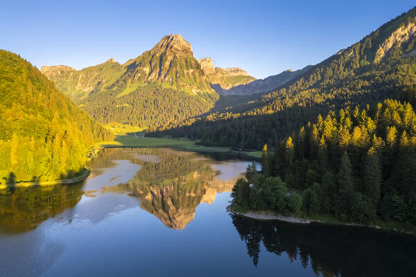 Aerial view of Barensoolspitz and Brunnelistock peaks at sunrise reflected in the Obersee lake. Näfels, Oberseealp, Canton of  Glarus, Switzerland.