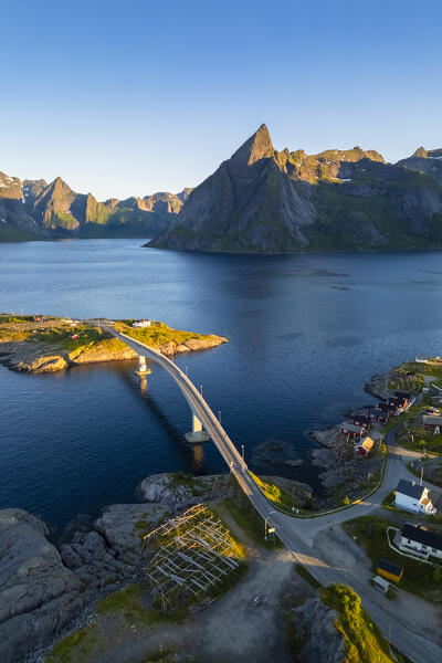 Aerial view of Olstinden mountain and Sakrisøya island in Reine Bay during sunrise at midnight sun in summer. Lofoten Islands, Norway.