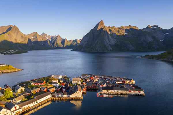 Aerial view of Olstinden mountain and Sakrisøya island in Reine Bay during sunrise at midnight sun in summer. Lofoten Islands, Norway.