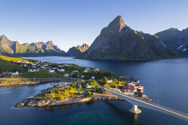 Aerial view of Olstinden mountain and Sakrisøya island in Reine Bay during sunrise at midnight sun in summer. Lofoten Islands, Norway.