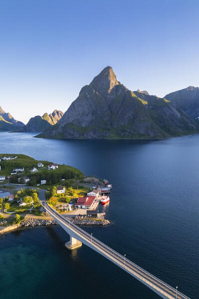 Aerial view of Olstinden mountain and Sakrisøya island in Reine Bay during sunrise at midnight sun in summer. Lofoten Islands, Norway.