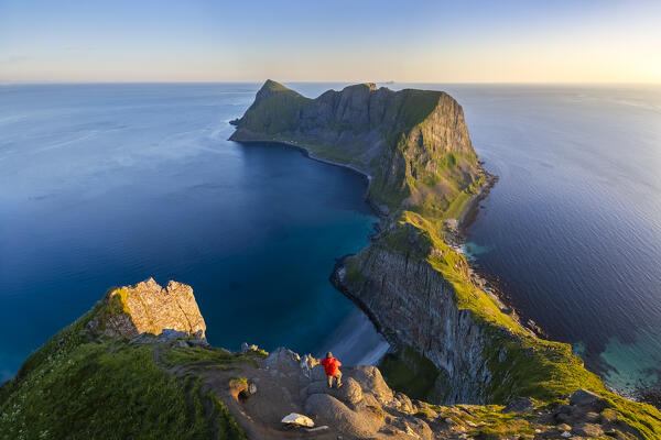 View of a meno admiring the end of Vaeroy island during midnight sun in summer. Sorland, Vaeroy, Nordland, Lofoten, Norway, Europe.