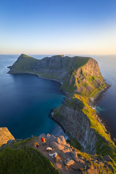 View of a meno admiring the end of Vaeroy island during midnight sun in summer. Sorland, Vaeroy, Nordland, Lofoten, Norway, Europe.