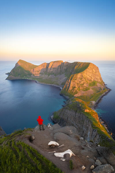 View of a meno admiring the end of Vaeroy island during midnight sun in summer. Sorland, Vaeroy, Nordland, Lofoten, Norway, Europe.