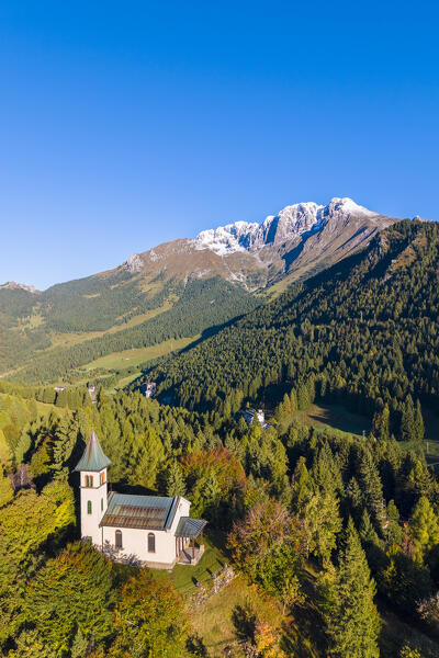 Aerial view of the Silvestri church and the Presolana massif after an autumnal snowfall at sunrise. Presolana pass, Castione della Presolana, Seriana Valley, Bergamo province, Lombardy, Italy.