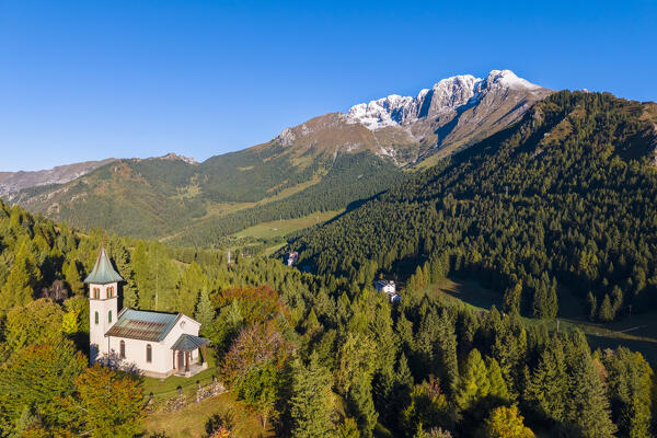 Aerial view of the Silvestri church and the Presolana massif after an autumnal snowfall at sunrise. Presolana pass, Castione della Presolana, Seriana Valley, Bergamo province, Lombardy, Italy.