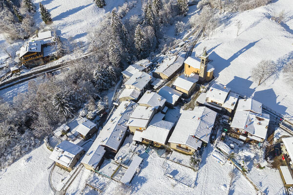 Aerial view of the small town of Rusio in Castione della Presolana after a snowfall in winter. Val Seriana, Bergamo district, Lombardy, Italy.