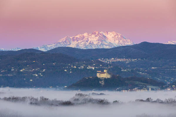 View of the fortress called Rocca di Angera during a winter sunrise with Monte Rosa in the background. Taino, Lake Maggiore, Varese district, Lombardy, Italy.