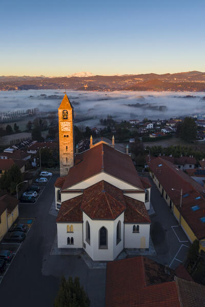Aerial view of the Chiesa di Santo Stefano Protomartire during a winter sunrise with Monte Rosa and Rocca d'Angera in the background. Taino, Lake Maggiore, Varese district, Lombardy, Italy.