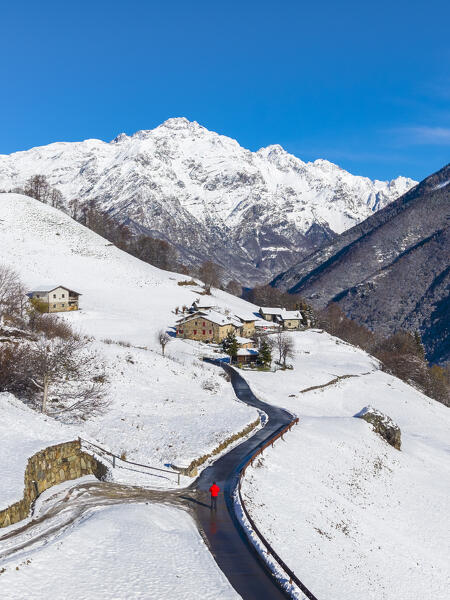 Aerial view of the church of Ripa di Gromo and the valley below after a snowfall in winter. Gromo, Val Seriana, Bergamo province, Lombardy, Italy, Europe.
