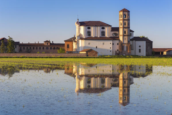 Abbey of Lucedio reflecting on rice fields at sunset, Trino Vercellese, Piedmont, Italy.