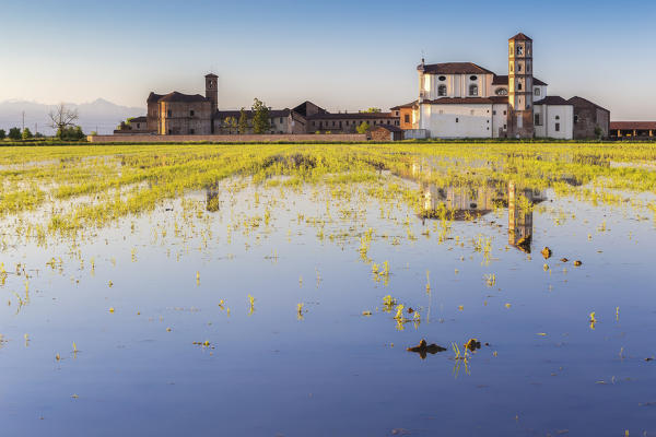 The Abbey of the Principality of Lucedio reflects on paddies at sunset. Trino Vercellese, Piedmont, Italy.