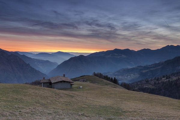 Winter sunset at the huts of Monte Alino over the town of Parre, Val Seriana, Bergamo province, Lombardy, Italy.