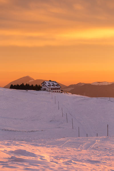 View of the Magnolini refuge during a winter sunset from Monte Pora, Val Seriana, Bergamo district, Lombardy, Italy.