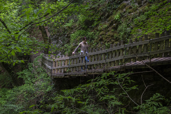 A girl walking on a wooden catwalk on the trail of the Breggia gorges, Muggio Valley, Mendrisio District, Canton Ticino, Switzerland.