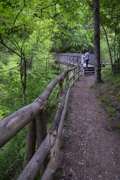 A girl walking on a wooden bridge on the trail of the Breggia gorges, Muggio Valley, Mendrisio District, Canton Ticino, Switzerland.
