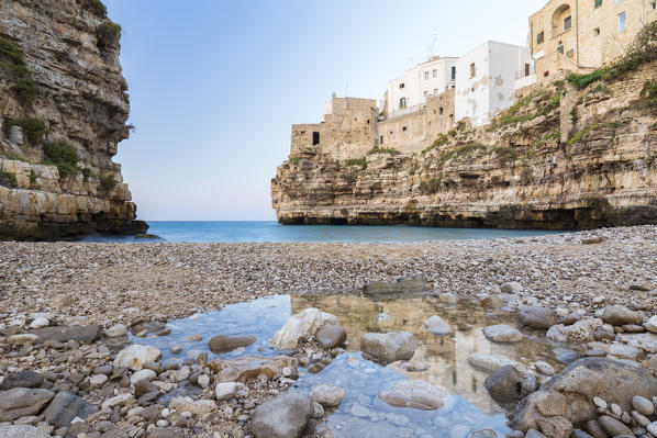 The overhanging houses of Polignano a Mare reflecting on a pond in the beach of Lama Monachile Cala Porto. Bari district, Apulia, Italy, Europe.
