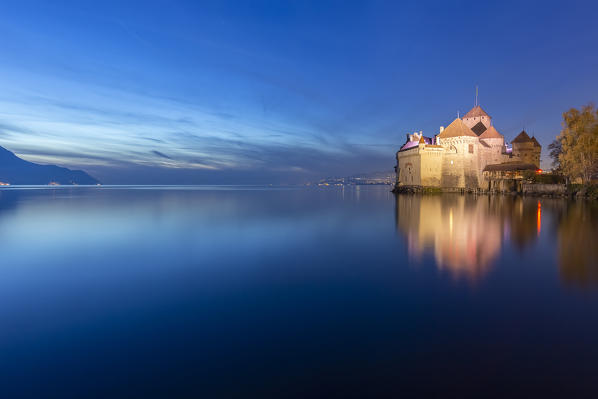 View of the Chillon castle on Lake Geneva at the blue hour. Veytaux, Montreux, Canton of Vaud, Switzerland.