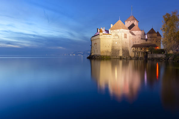 View of the Chillon castle on Lake Geneva at the blue hour. Veytaux, Montreux, Canton of Vaud, Switzerland.
