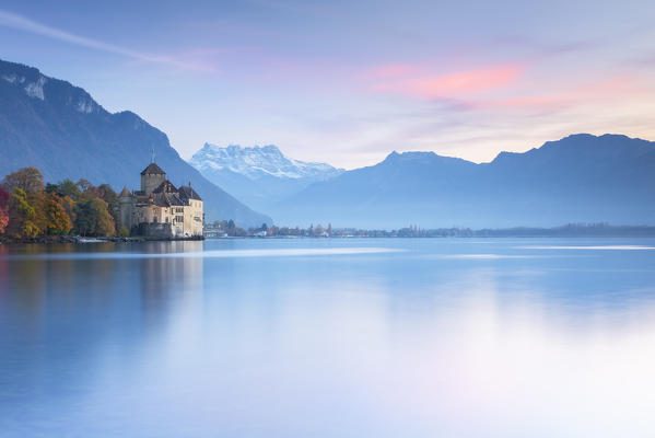 View of the Chillon castle on Lake Geneva and Dents du Midi at sunset. Veytaux, Montreux, Canton of Vaud, Switzerland.