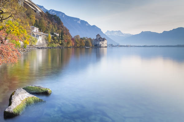 View of the Chillon castle on Lake Geneva and Dents du Midi at sunset. Veytaux, Montreux, Canton of Vaud, Switzerland.