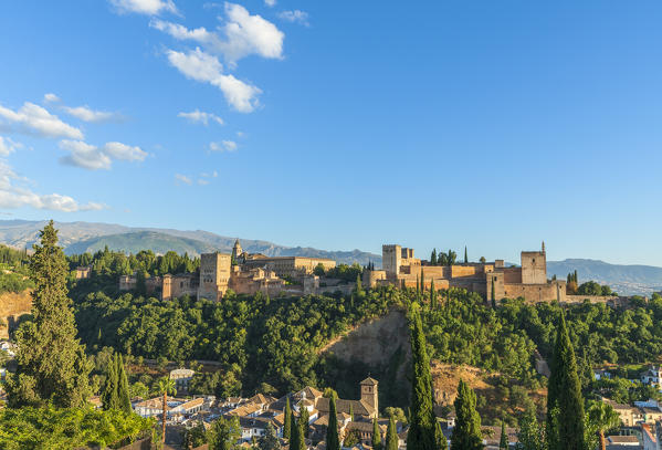 The Alhambra palace and fortress complex surrounded by woods and Sierra Nevada mountain range, Granada, Andalusia, Spain