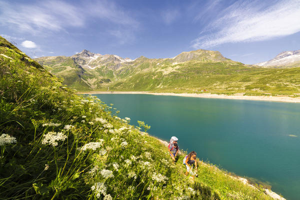 Hikers with baby in backpack on shore of Lake Montespluga, Chiavenna Valley, Sondrio province, Valtellina, Lombardy, Italy