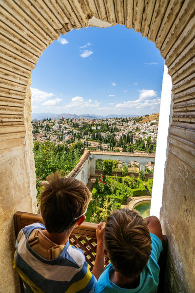 Two children look at Patio de la Sultana (Court of the Sultana’s Cypress Tree) from mirador on top of Generalife Palace, Granada, Andalusia, Spain