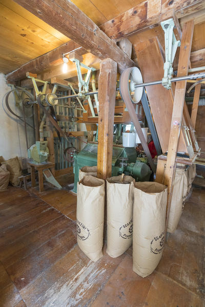 Machinery for millstone and wheat in jute bags, Molino Scartazzini, Promontogno, Maloja, Graubunden, Val Bregaglia, Switzerland