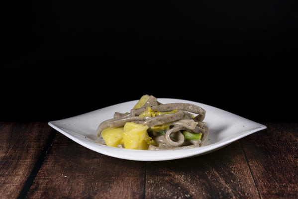 Dish of Pizzoccheri on wood table background, Valtellina, Lombardy, Italy