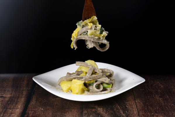 Dish of Pizzoccheri on wood table background, Valtellina, Lombardy, Italy