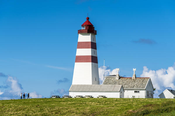Tourists walking towards Alnes Lighthouse, Godoya Island, Alesund, More og Romsdal County, Norway