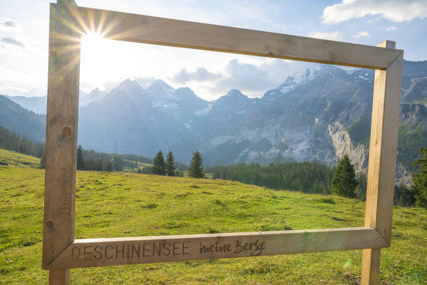 Wood signage on green meadow framing the Swiss Alps at Oeschinensee, Bernese Oberland, Kandersteg, Canton of Bern, Switzerland