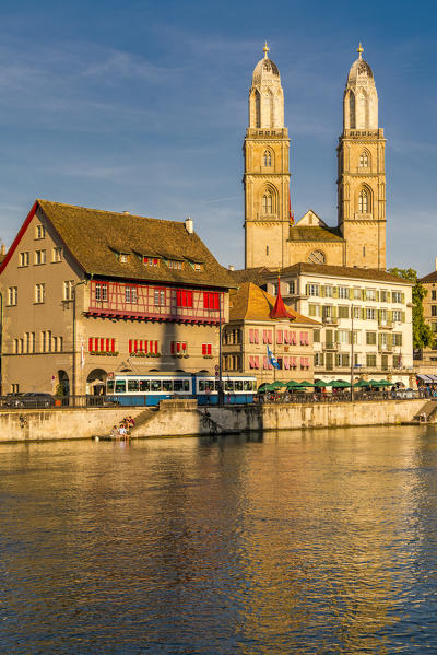 Tram at Limmatquai on banks of Limmat River with Grossmunster church in background, Zurich, Switzerland
