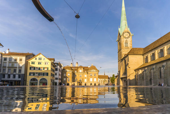 Fraumunster bell tower and houses mirrored in Munsterhof fountain, Zurich, Switzerland