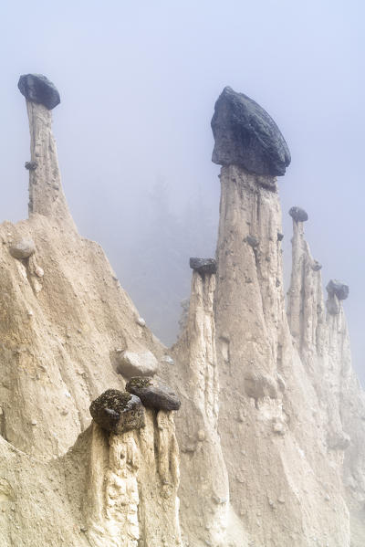 Natural rock spires of the Earth Pyramids emerging from fog, Perca/Percha, province of Bolzano, South Tyrol, Italy