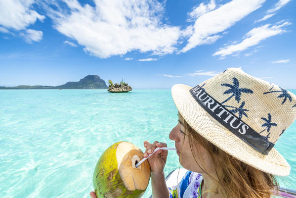 Beautiful woman drinking coconut water close to Crystal Rock in the tropical lagoon, La Gaulette, Le Morne, Indian Ocean, Mauritius