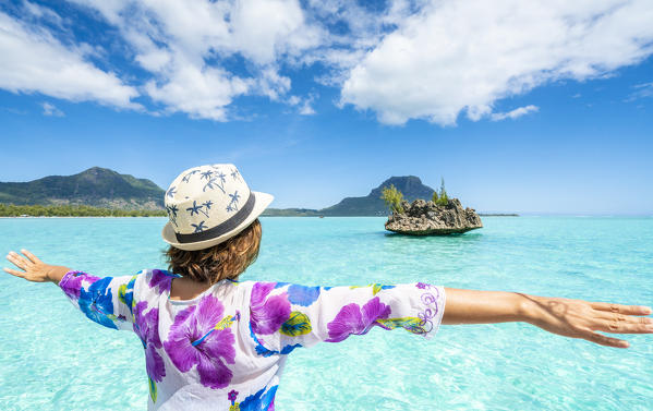 Cheerful woman with outstretched arms admiring Crystal Rock and lagoon, La Gaulette, Le Morne Brabant, Indian Ocean, Mauritius