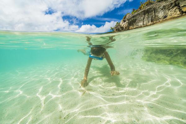 Cute little boy snorkeling in the clear sea approaching starfish, Ile aux Aigrettes, Pointe d'Esny, Mahebourg, Indian Ocean, Mauritius
