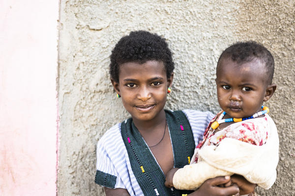 Portrait of smiling girl holding a baby child in her arms, Abala, Afar Region, Ethiopia, Africa