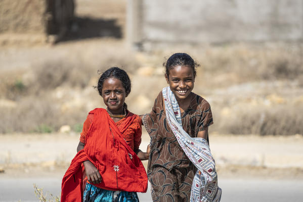 Two little girls with traditional colorful clothing smiling at camera, Abala, Afar Region, Ethiopia, Africa