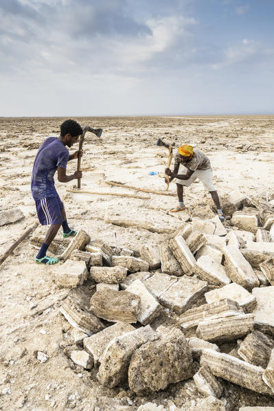 Two miners breaking up salt blocks in the salt flat, Danakil Depression, Afar Region, Ethiopia, Africa