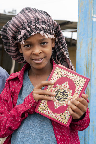 Portrait of young muslim boy showing the holy Koran book, Bati, Amhara Region, Oromia, Ethiopia, Africa