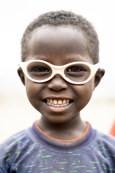 Cute little boy with glasses smiling at camera, Melabday, Asso Bhole, Danakil Depression, Afar Region, Ethiopia, Africa