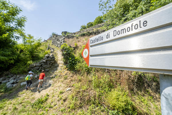 Two little boys running on path towards Domofole Castle, Costiera dei Cech, Mello, Valtellina, Sondrio province, Lombardy, Italy