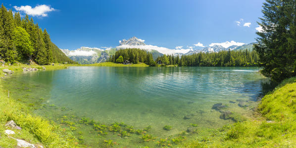 Panoramic of the clear water of Lake Arnisee surrounded by green woods, Canton Uri, Switzerland